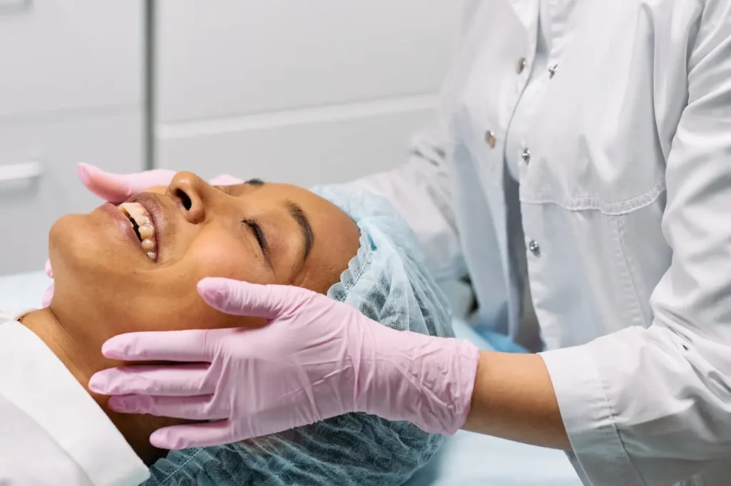 Fale com seu dermatologista e peça ultrassom microfocado Paciente deitada em maca enquanto sua pele é avaliada por dermatologista